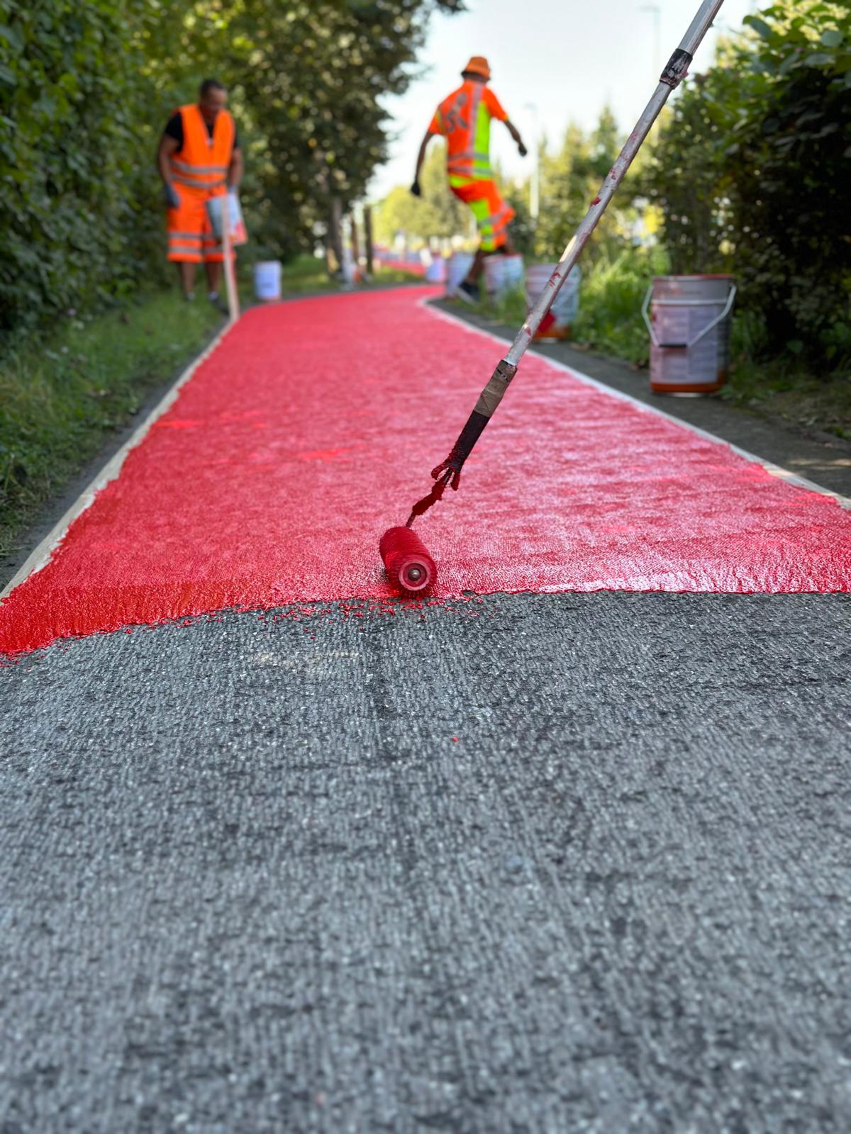 Aufbringen eines roten Radschutzstreifens mit der Rolle – Kaltplastik in Arbeit
