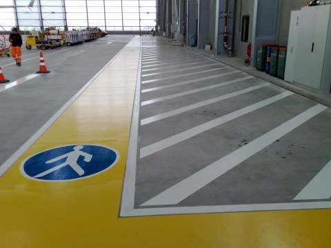 Hallenmarkierung mit Fußgängerweg und Betriebssicherheitszeichen – industrielle Verkehrsfläche