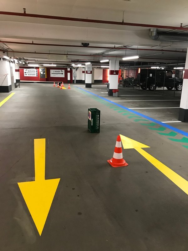 Gelbe Richtungspfeile und Leitmarkierungen im Parkhaus – frisch aufgebracht