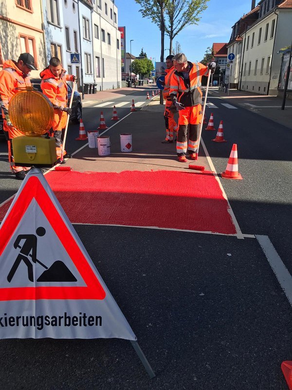 Kaltplastik-Schutzstreifen – Aufbringen roter Radwegmarkierung mit Warnzeichen