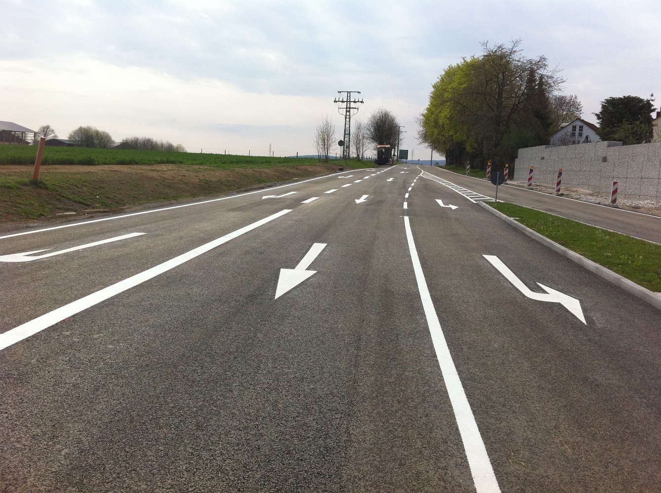 Landstraße mit Abbiegepfeilen und Fahrbahnmarkierungen – frisch markiert